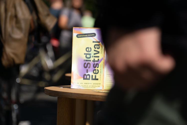 Ein Foto unseres Festival-Flyers vor einem verschwommenen Hintergrund.