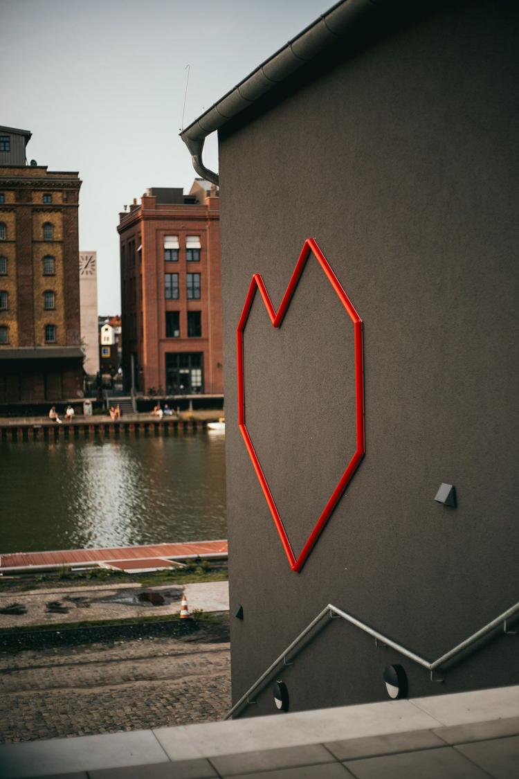 Ein Foto von der Dachterasse auf den Hafen. Im Fokus ist unser Logo als Fassadenbeleuchtung.